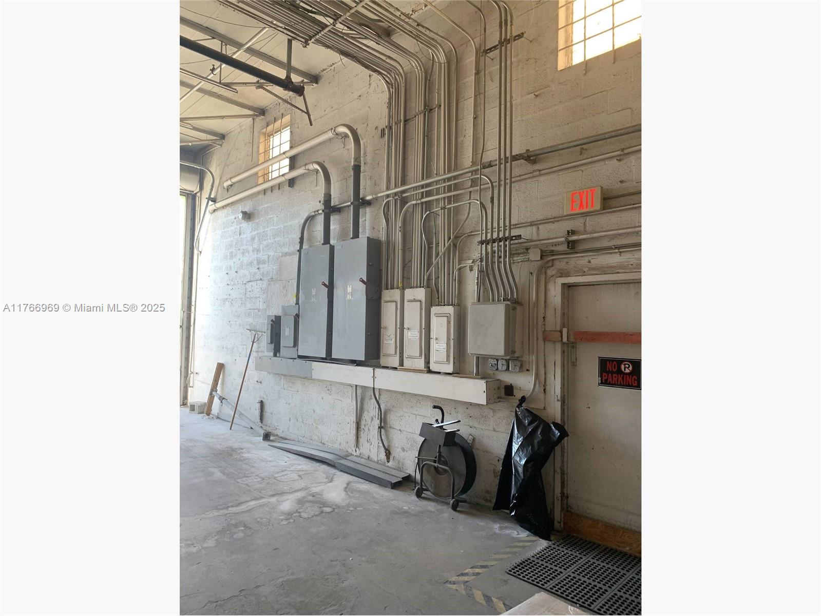 An industrial warehouse interior features exposed electrical conduit, metal breaker boxes, and a door — 1677 W 31st Pl # 1677, Hialeah FL 33012, HIALEAH, FL