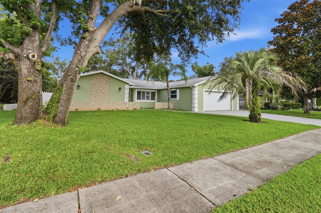 A single-story house with green stucco walls, stone accents, and a white garage door — 644 PEACHWOOD DRIVE, ALTAMONTE SPRINGS, FL