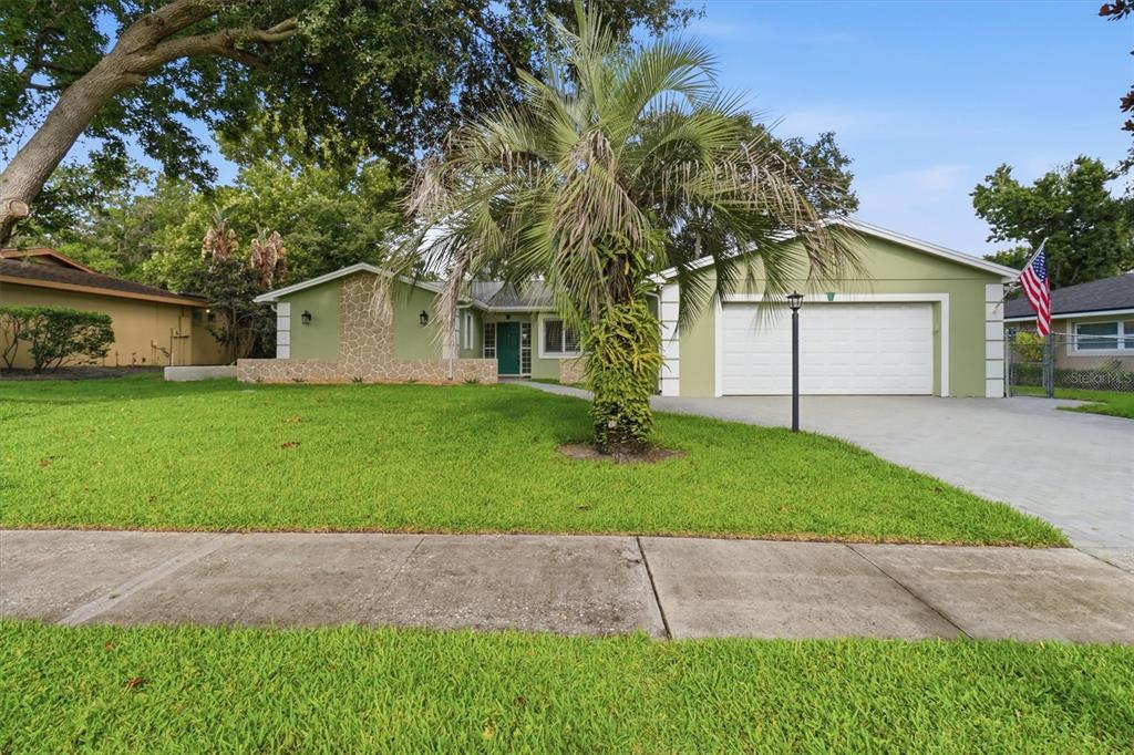 A single-story green house with a two-car garage, stone accents, and a palm tree — 644 PEACHWOOD DRIVE, ALTAMONTE SPRINGS, FL