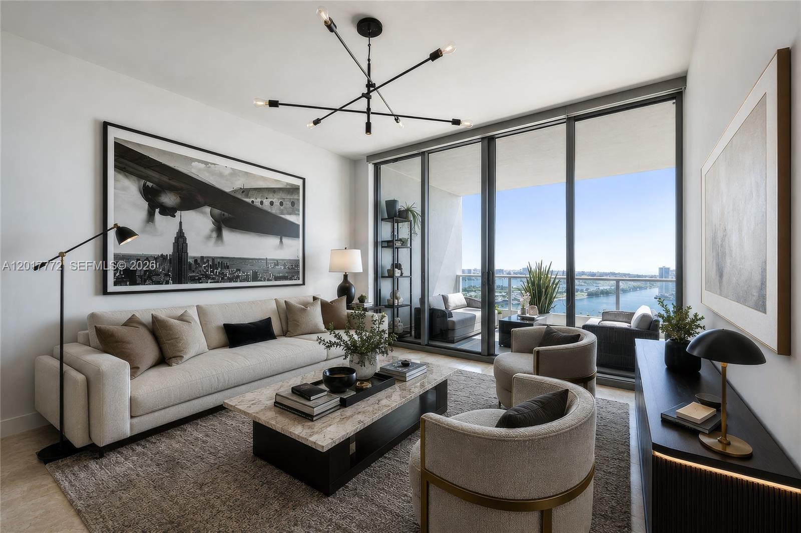 A modern living room features a beige sofa, marble coffee table, and floor-to-ceiling balcony windows — 900 Biscayne Blvd # 4205, Miami FL 33132, MIAMI, FL