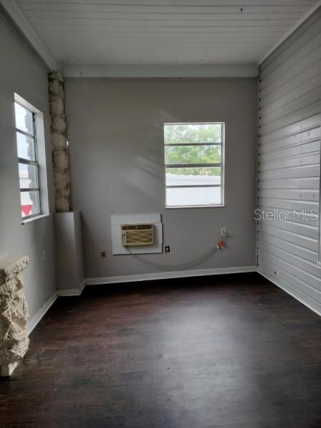 A room with dark wood-look flooring, light gray walls, two windows, and a window air conditioner — 103 E WARD AVENUE, EUSTIS, FL