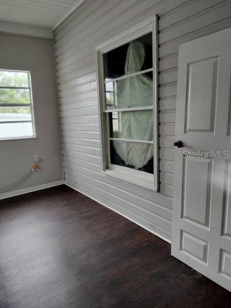 A room with dark wood-look flooring, light gray horizontal siding, and a white door — 103 E WARD AVENUE, EUSTIS, FL