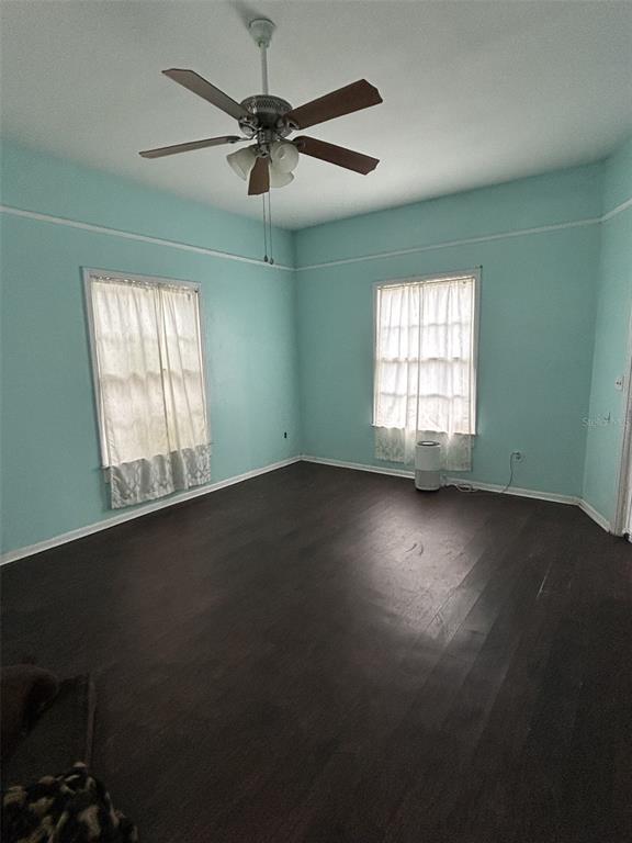 An empty room with light blue walls, dark wood floors, and a ceiling fan — 103 E WARD AVENUE, EUSTIS, FL