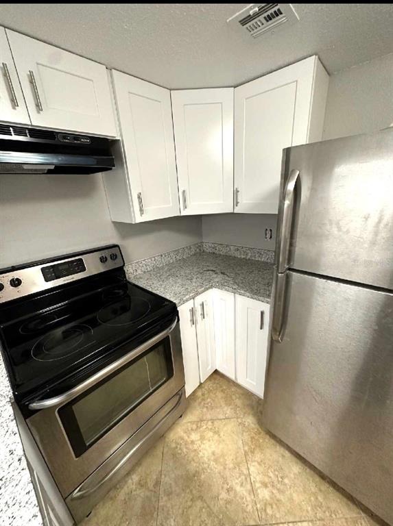 A kitchen features white cabinets, granite countertops, and stainless steel appliances — 4149 S SEMORAN BOULEVARD UNIT 17, ORLANDO, FL