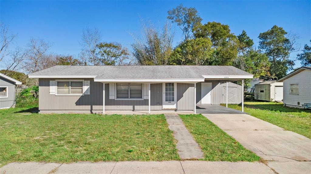 A single-story house with gray siding, a covered front porch, and a concrete driveway — 2373 FAIRGREN AVENUE, DELTONA, FL