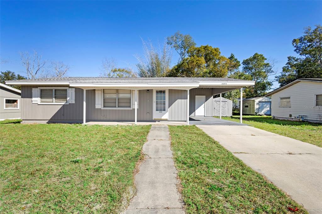 A single-story house with gray vertical siding, a front porch, and an attached carport — 2373 FAIRGREN AVENUE, DELTONA, FL