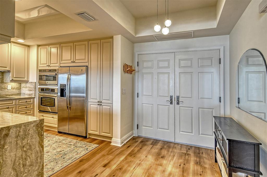 A kitchen with cream cabinets, stainless steel appliances, and double doors leading to an entryway — 50 CENTRAL AVENUE UNIT 15B, SARASOTA, FL