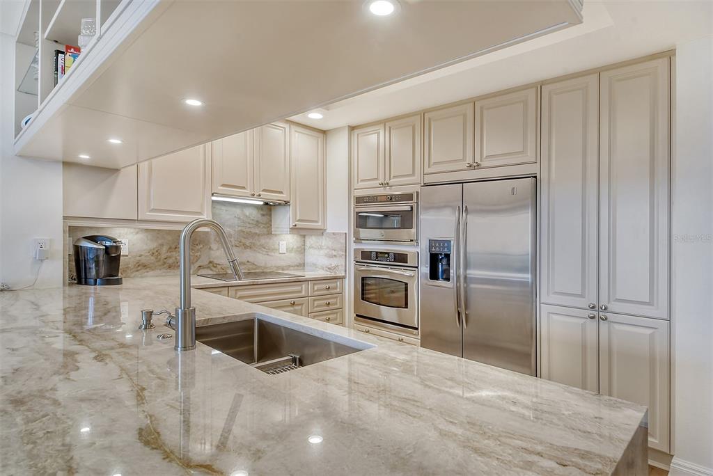 A kitchen with light-colored cabinets, stainless steel appliances, and a large stone-topped island — 50 CENTRAL AVENUE UNIT 15B, SARASOTA, FL