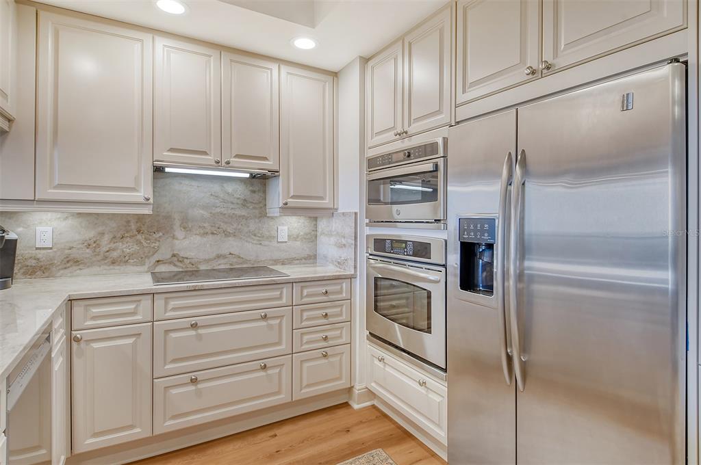 A kitchen with light-colored cabinets, stainless steel appliances, and a stone backsplash — 50 CENTRAL AVENUE UNIT 15B, SARASOTA, FL