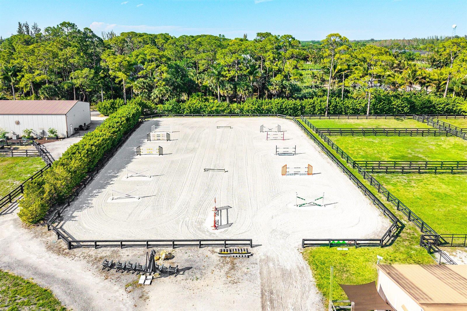 An aerial view shows a fenced equestrian riding arena with several jumps on sandy ground — 6149 Park Lane E, Lake Worth FL 33449, LAKE WORTH, FL