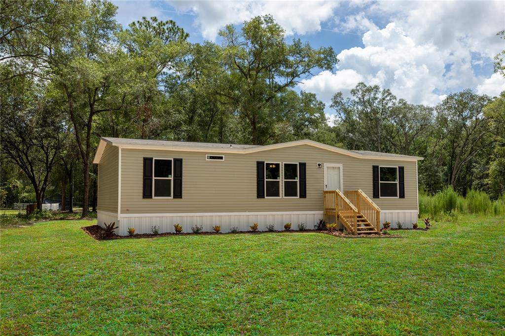 A single-story manufactured home with light green siding and black shutters sits on a lawn — 104 JACKSON AVENUE, INTERLACHEN, FL