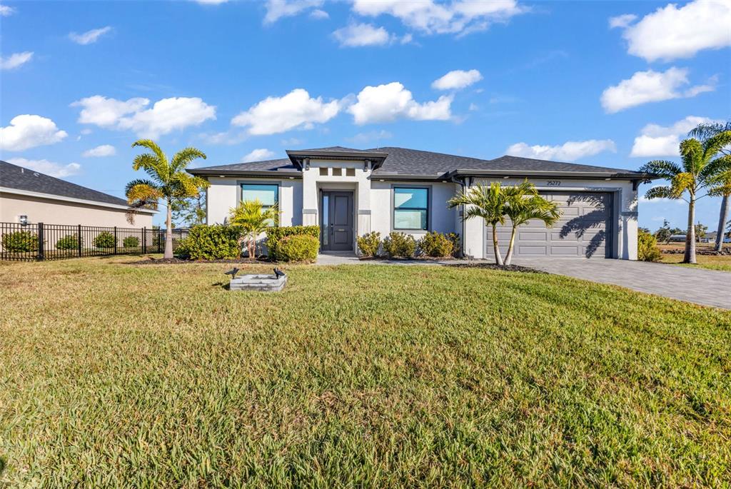 A single-story house with a gray exterior, a paved driveway, and palm trees in front — 25272 DOREDO DRIVE, PUNTA GORDA, FL