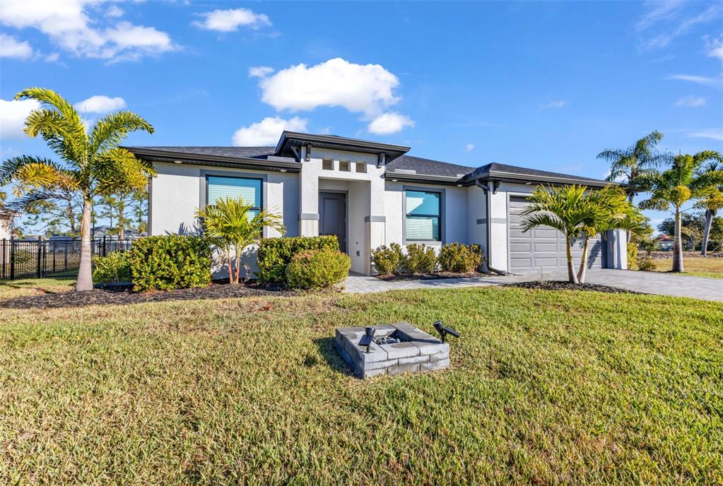 A single-story house with a gray garage, palm trees, and a stone fire pit — 25272 DOREDO DRIVE, PUNTA GORDA, FL