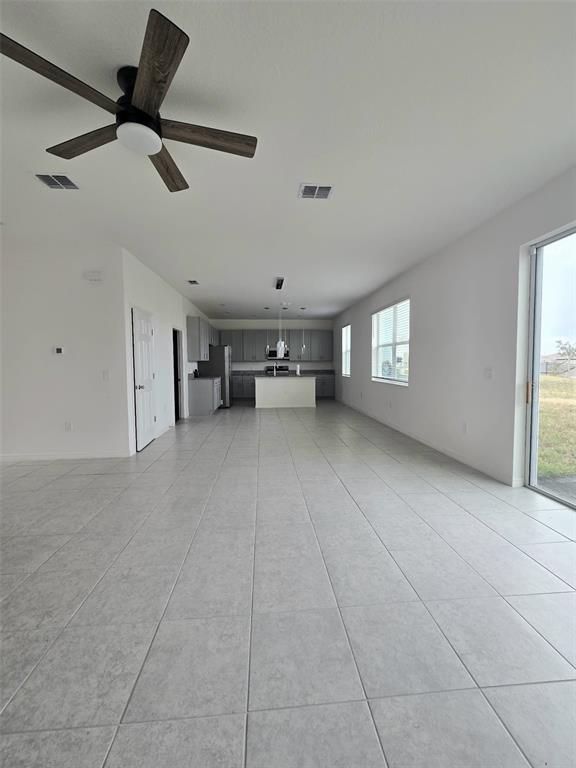 An open-concept kitchen and living area features light tile flooring, gray cabinetry, and a ceiling fan — 1603 GARDINER STREET, HAINES CITY, FL