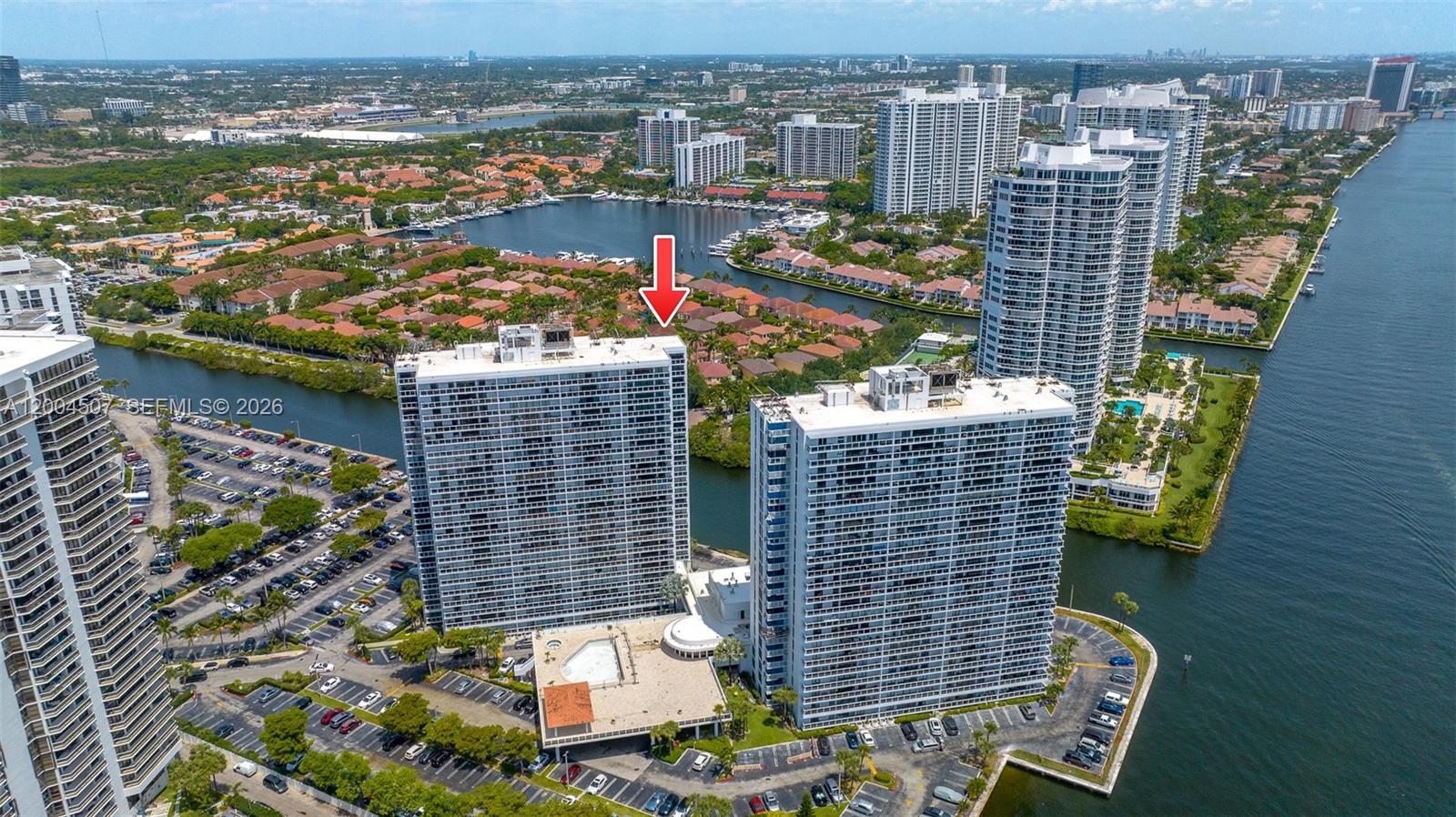 An aerial view shows two tall residential towers situated along a waterway with parking lots — 20505 E Country Club Dr # 38, Aventura FL 33180, AVENTURA, FL
