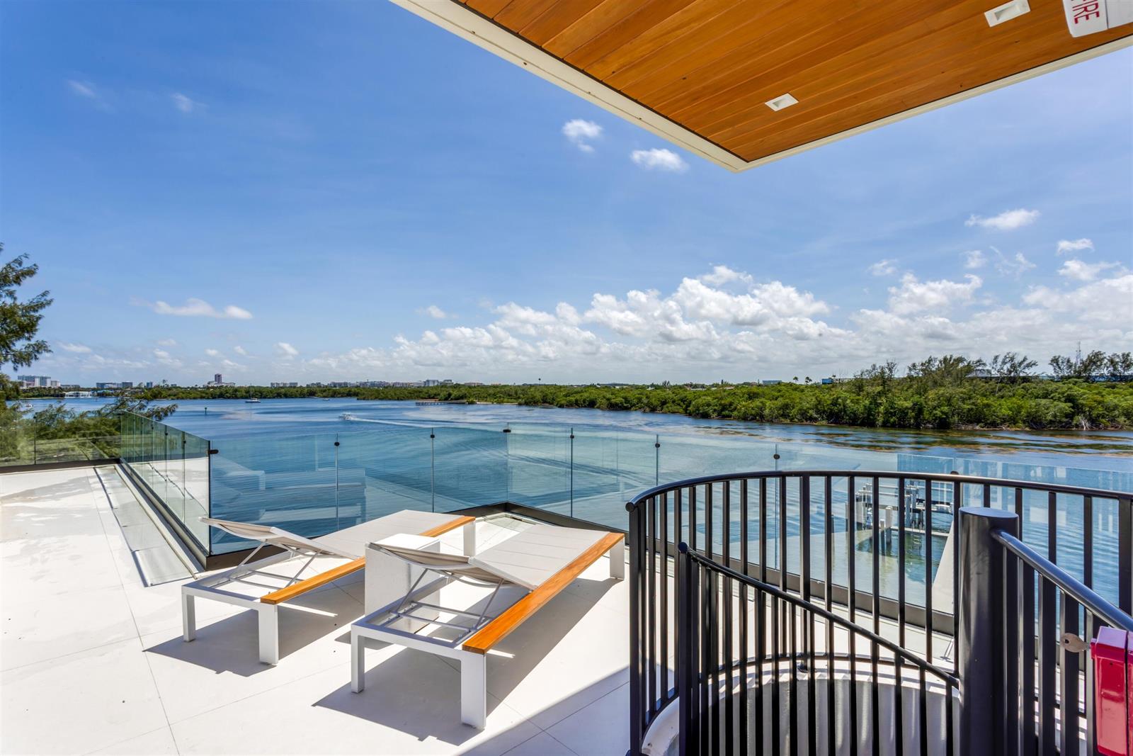 A modern balcony features two lounge chairs, a glass railing, and a spiral staircase — 900 Lago Mar Lane, Boca Raton FL 33431, BOCA RATON, FL