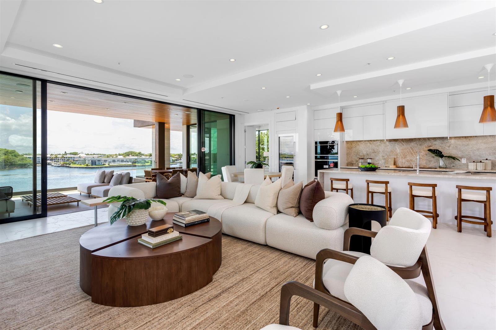 A modern open-concept living room and kitchen with a large sectional overlooking a waterfront patio — 900 Lago Mar Lane, Boca Raton FL 33431, BOCA RATON, FL