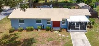 An aerial view of a blue single-story house with a metal roof and screened porch — 709 CINDY AVENUE, FRUITLAND PARK, FL