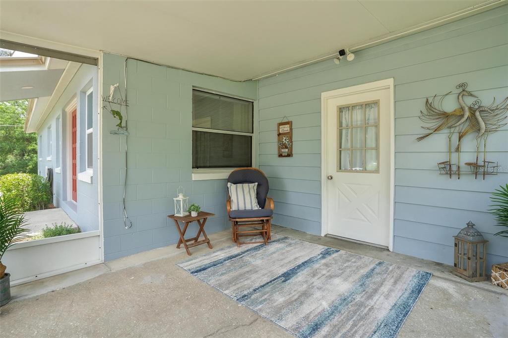 A covered porch with light blue siding, a rocking chair, and a white door — 709 CINDY AVENUE, FRUITLAND PARK, FL