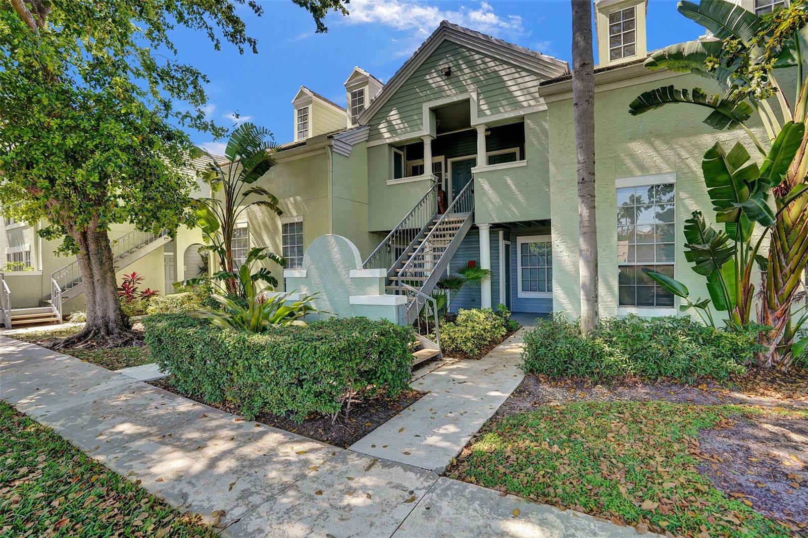 A two-story light green apartment building with an exterior staircase and lush landscaping — 1050 Crystal Way, Delray Beach FL 33444, DELRAY BEACH, FL