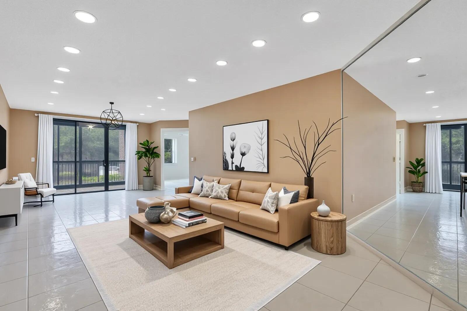 A living room with tan walls, a leather sectional, tile floors, and a large mirror — 5155 Europa Drive # I, Boynton Beach FL 33437, BOYNTON BEACH, FL