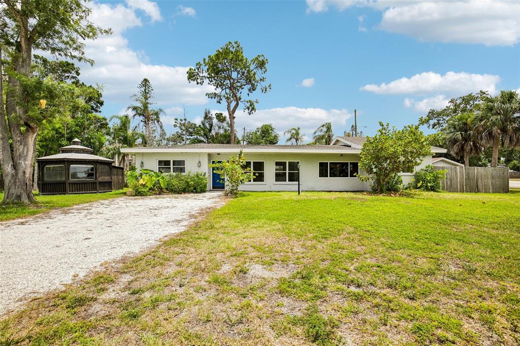 A single-story house with a white exterior, a gravel driveway, and a gazebo on the left — 807 LUCILLE AVENUE, NOKOMIS, FL