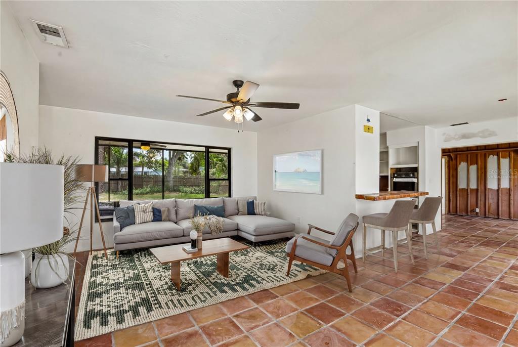 A living room features a sectional sofa, a patterned rug, and terracotta tile flooring — 807 LUCILLE AVENUE, NOKOMIS, FL