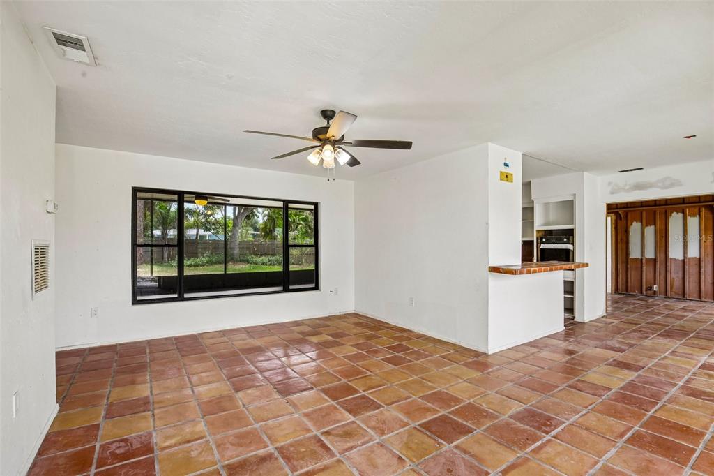 A living room with terracotta tile flooring, a ceiling fan, and a large window — 807 LUCILLE AVENUE, NOKOMIS, FL