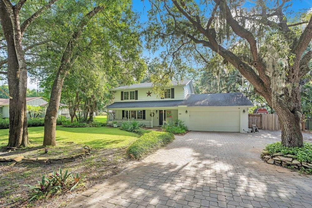 A two-story house with a paved driveway, a front porch, and large oak trees — 725 OAKDALE STREET, WINDERMERE, FL