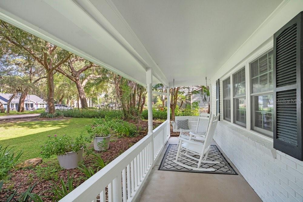 A covered front porch features white railings, two rocking chairs, and a patterned rug — 725 OAKDALE STREET, WINDERMERE, FL
