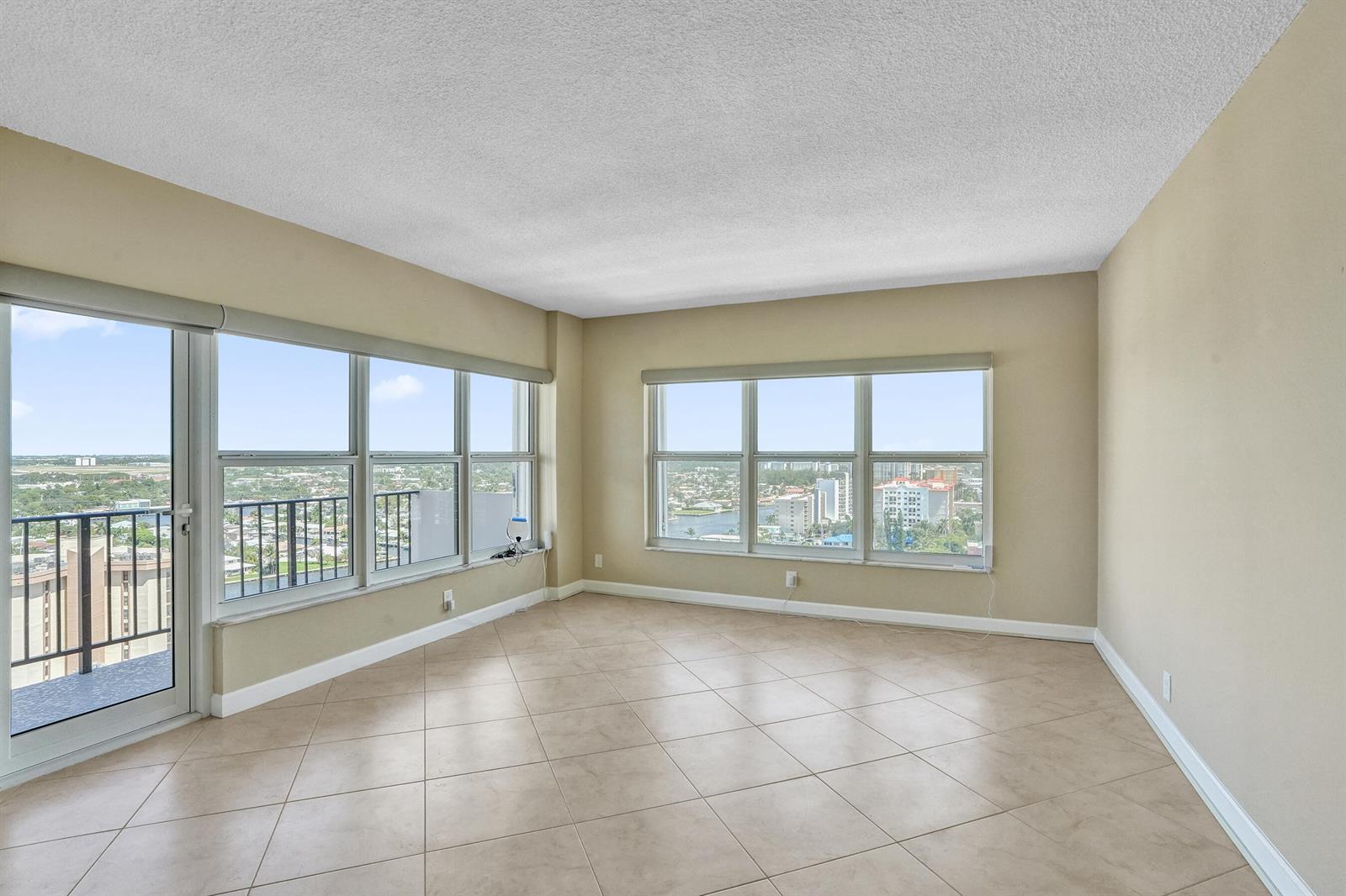 An empty room with beige walls, tile flooring, and large windows overlooking a city skyline — 405 N Ocean Boulevard # 1929, Pompano Beach FL 33062, POMPANO BEACH, FL