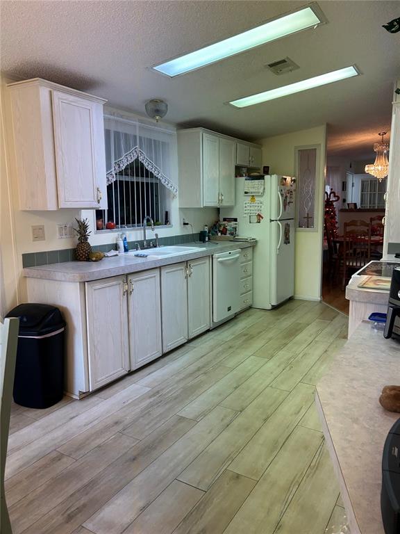 A kitchen features light wood cabinets, laminate countertops, wood-look flooring, and two rectangular ceiling lights — 263 SUE AVENUE, DAVENPORT, FL