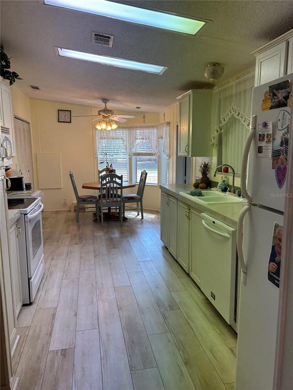 A kitchen with light wood-look tile flooring, white cabinets, and a dining area with windows — 263 SUE AVENUE, DAVENPORT, FL