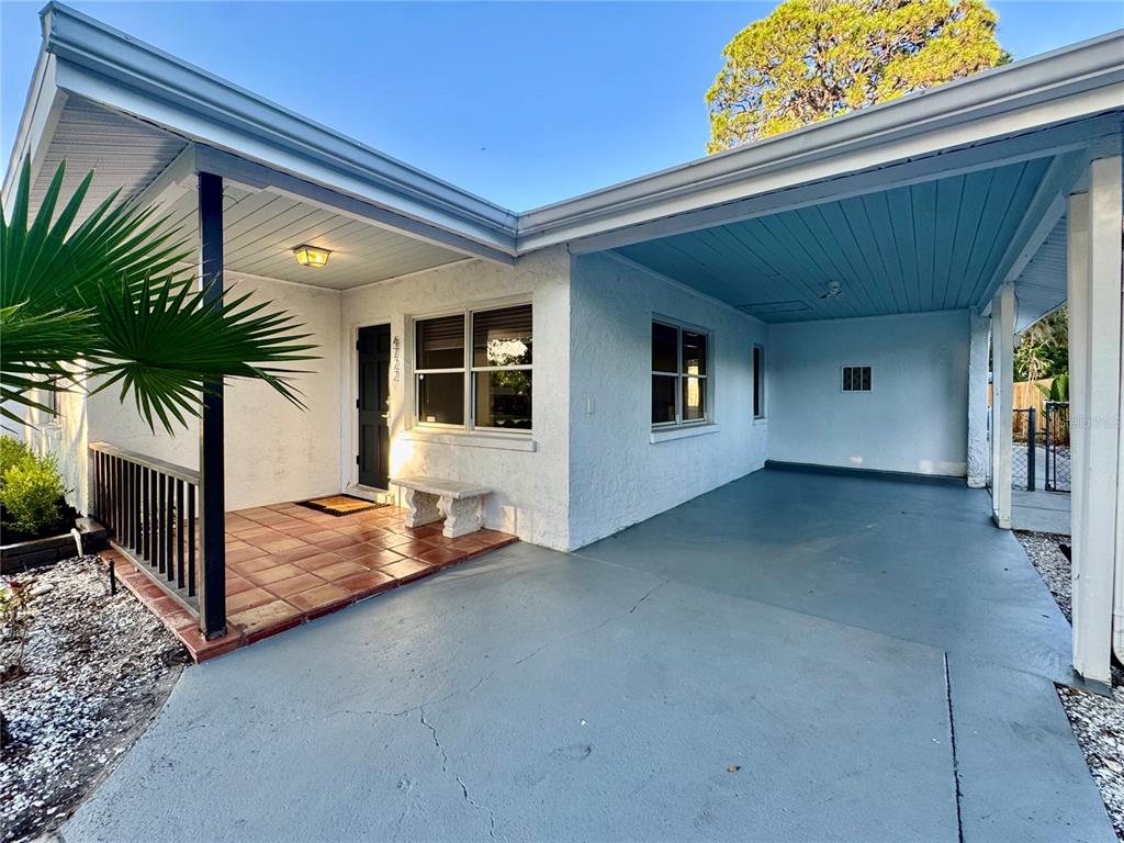The exterior of a white house features a tiled front porch and a covered carport — 4722 STEVENS DRIVE, SARASOTA, FL