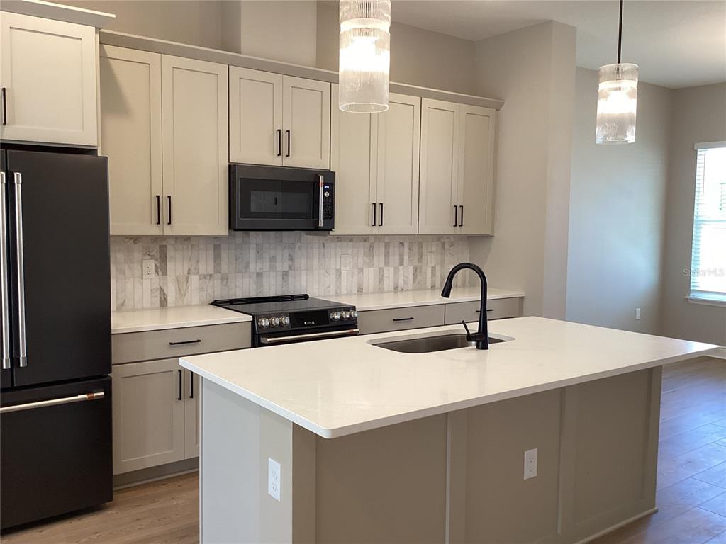 A kitchen features light-colored cabinetry, a black refrigerator, a center island, and a tile backsplash — 13419 LEMON ORCHARD BEND, WINDERMERE, FL