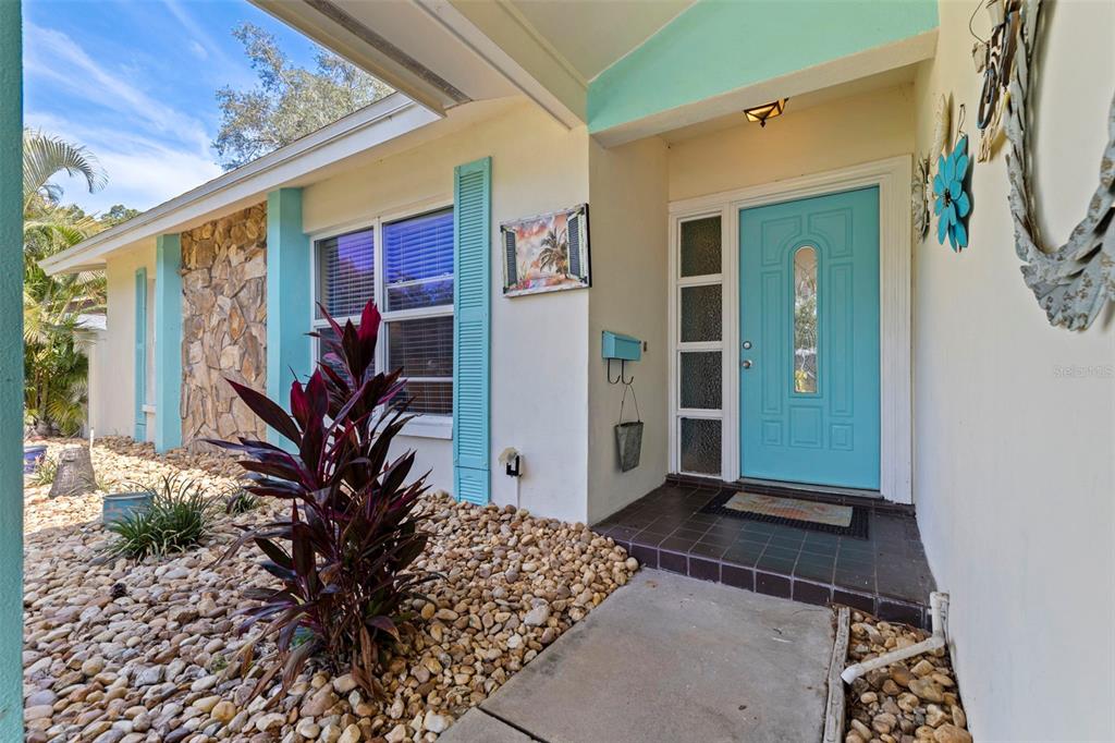 The exterior of a house features a bright blue front door and rock landscaping — 201 58TH AVENUE S, ST PETERSBURG, FL