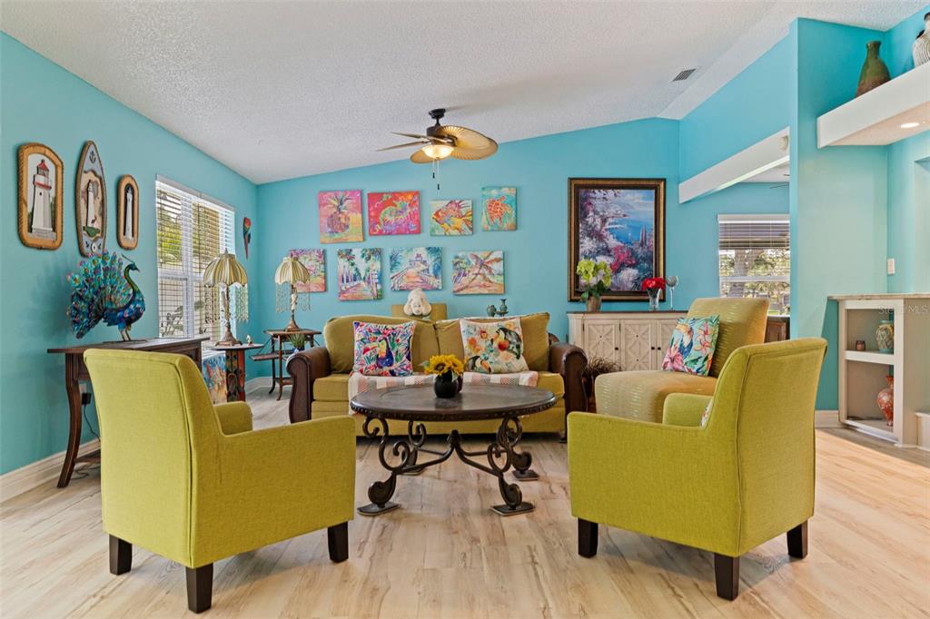 A living room with light blue walls, lime green armchairs, a sofa, and colorful wall art — 201 58TH AVENUE S, ST PETERSBURG, FL