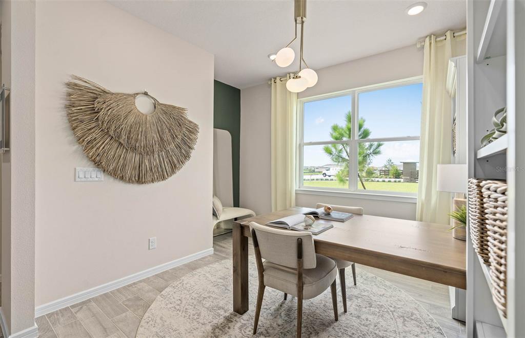 A dining room features a wooden table, chairs, a circular rug, and a wall decoration — 2615 HAMMOCK HARBOR AVENUE, ST CLOUD, FL