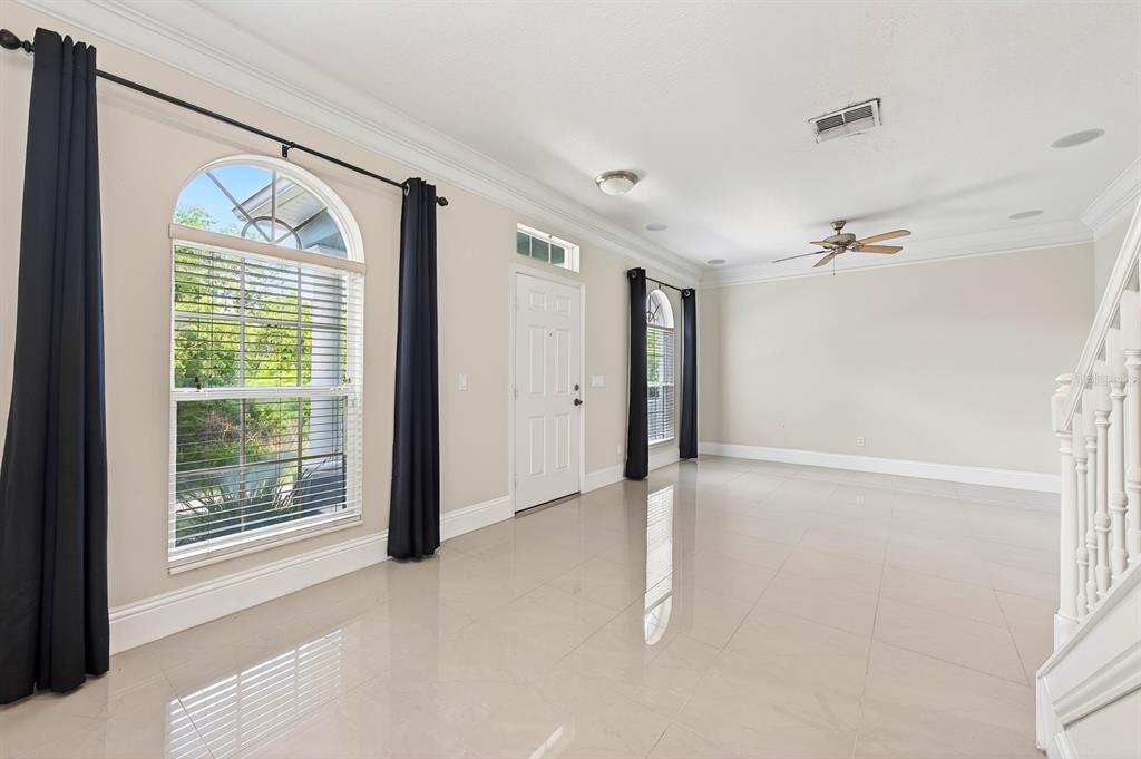 A bright, empty living room with light tile floors, arched windows, and a ceiling fan — 6390 SOUTHBRIDGE STREET, WINDERMERE, FL