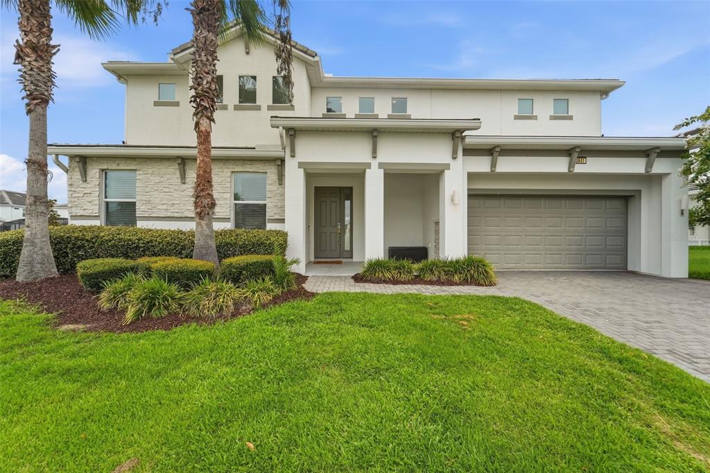 A two-story house with a stone facade, a gray garage door, and a front walkway — 3841 SONOMA BOULEVARD, KISSIMMEE, FL