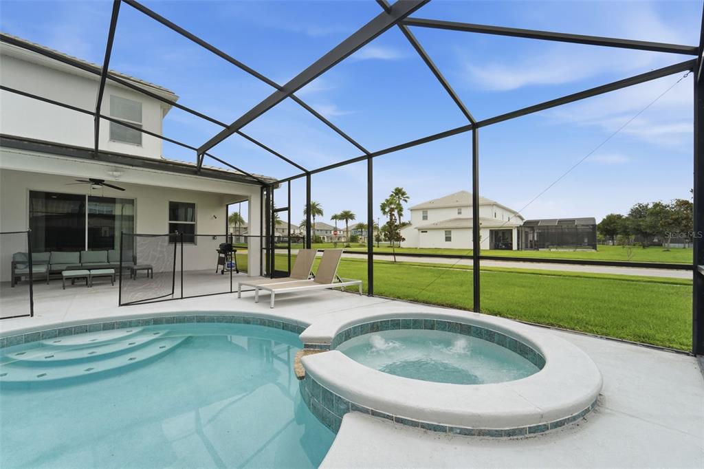 A screened-in patio features a swimming pool, a hot tub, and lounge chairs — 3841 SONOMA BOULEVARD, KISSIMMEE, FL