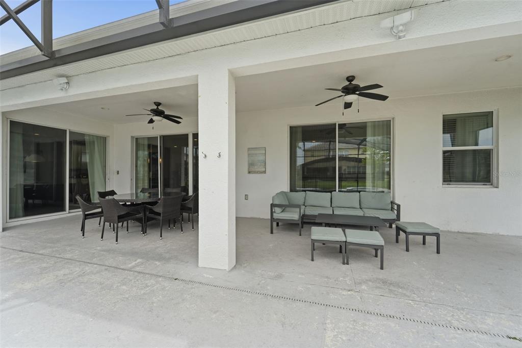 A covered patio features a dining area, a seating area with a sofa, and ceiling fans — 3841 SONOMA BOULEVARD, KISSIMMEE, FL