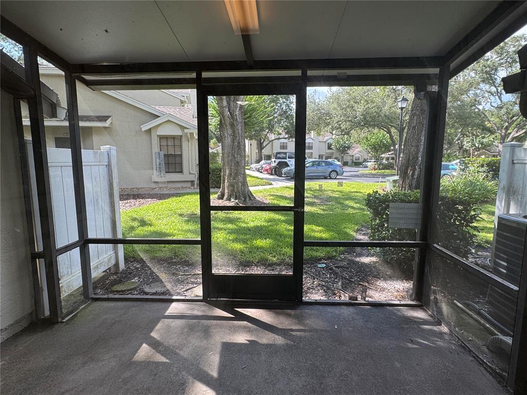 A screened-in porch with a concrete floor looking out onto a grassy residential courtyard — 5100 BURCHETTE ROAD UNIT 1201, TAMPA, FL