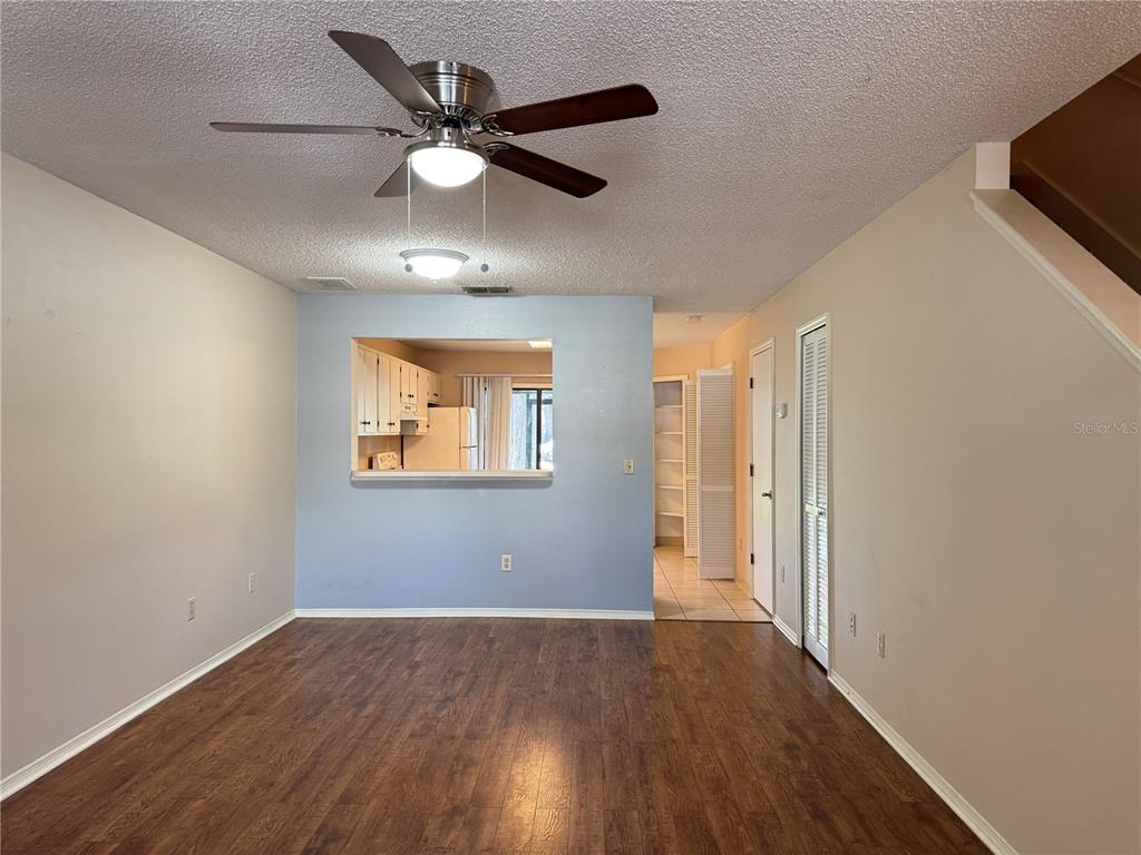 A living room with wood-look flooring, a ceiling fan, and a kitchen pass-through window — 5100 BURCHETTE ROAD UNIT 1201, TAMPA, FL