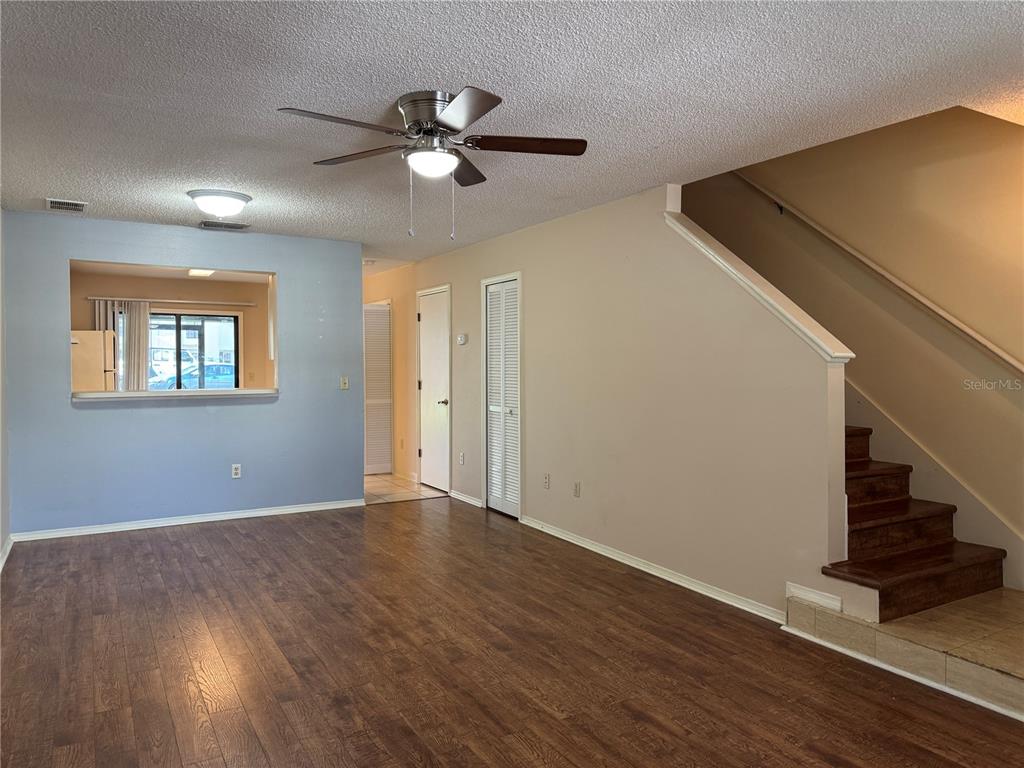 A living room with wood-look flooring, a ceiling fan, and stairs leading to an upper level — 5100 BURCHETTE ROAD UNIT 1201, TAMPA, FL