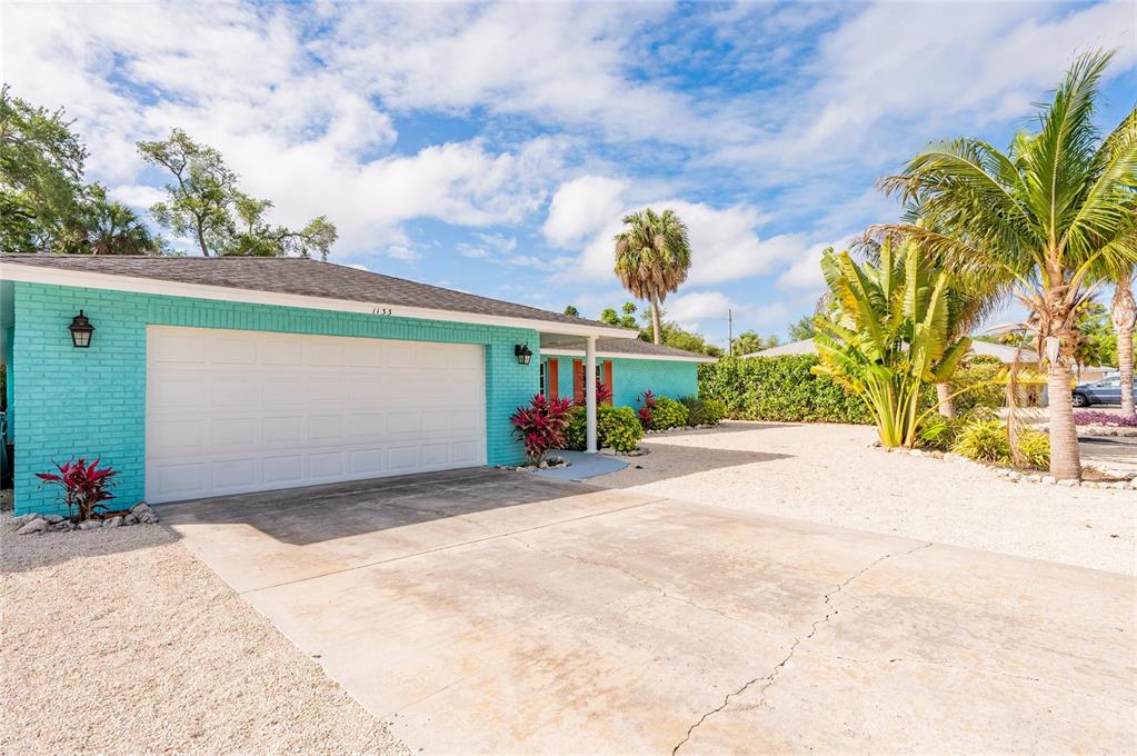 A turquoise brick house with a white garage door and a gravel driveway — 1133 MONTEZUMA DRIVE, BRADENTON, FL