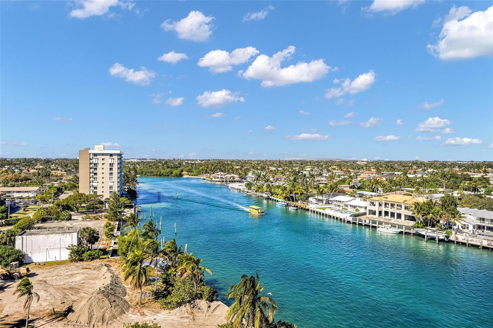 An aerial view shows a waterway lined with houses, palm trees, and a tall building — 2639 N Riverside Drive # 1005, Pompano Beach FL 33062, POMPANO BEACH, FL