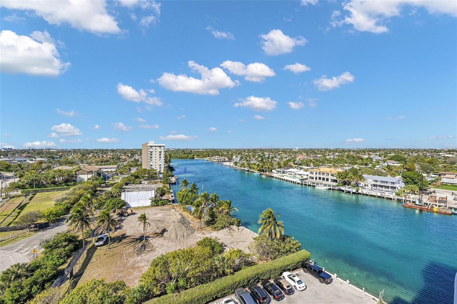 An aerial view shows a waterway flanked by residential buildings, palm trees, and a parking lot — 2639 N Riverside Drive # 1005, Pompano Beach FL 33062, POMPANO BEACH, FL