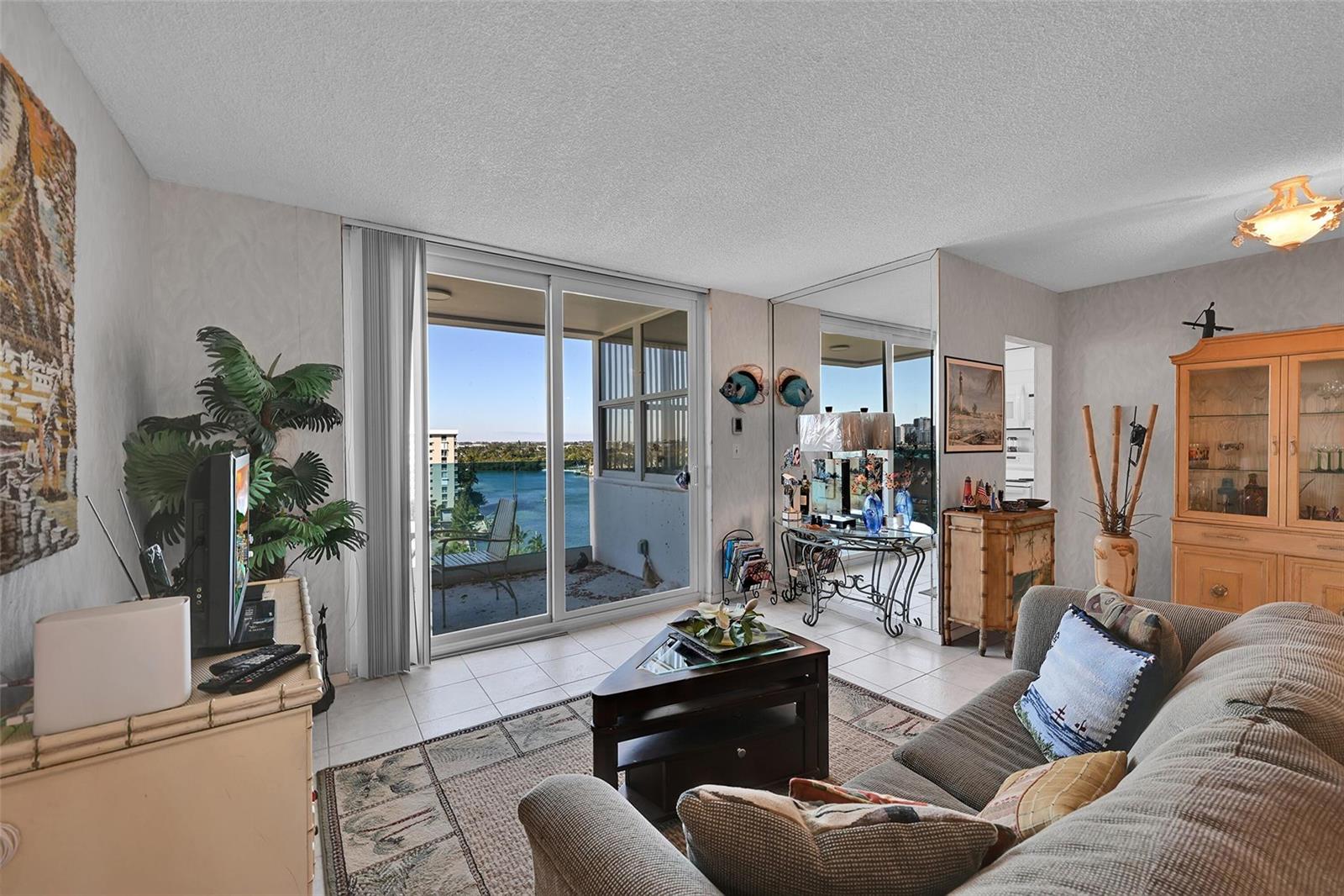 A living room features a sofa, a coffee table, and a sliding door to a balcony — 2639 N Riverside Drive # 1005, Pompano Beach FL 33062, POMPANO BEACH, FL