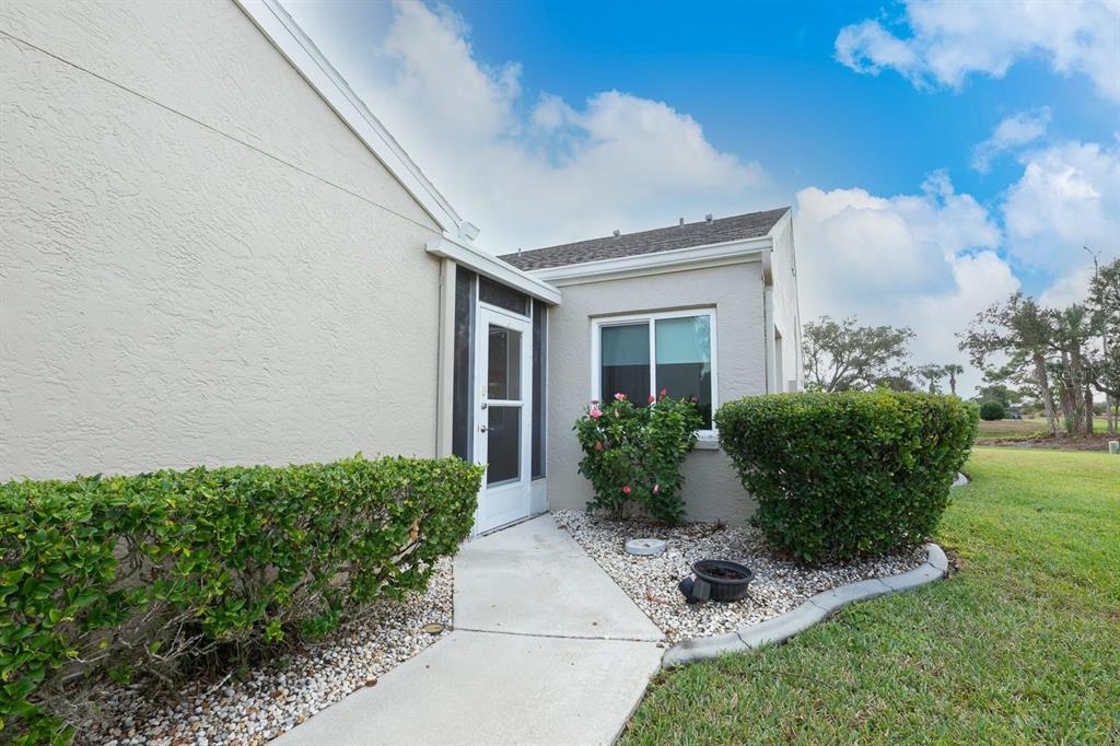 A concrete walkway leads to a white screen door on the side of a house — 12235 SW KINGSWAY CIRCLE UNIT C6, ARCADIA, FL